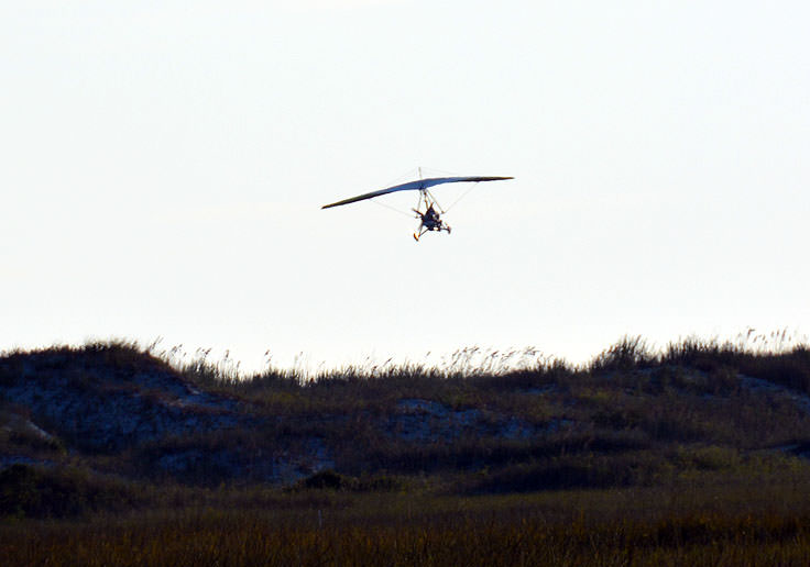 An ultralight aircraft flies over Sunset Beach, NC